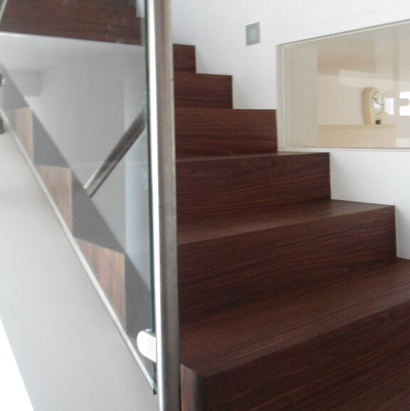 Moderne aufgesattelte Treppe aus amerikanischem Nussbaum. Die Setzstufen sind zum Treppenauge geschlossen.